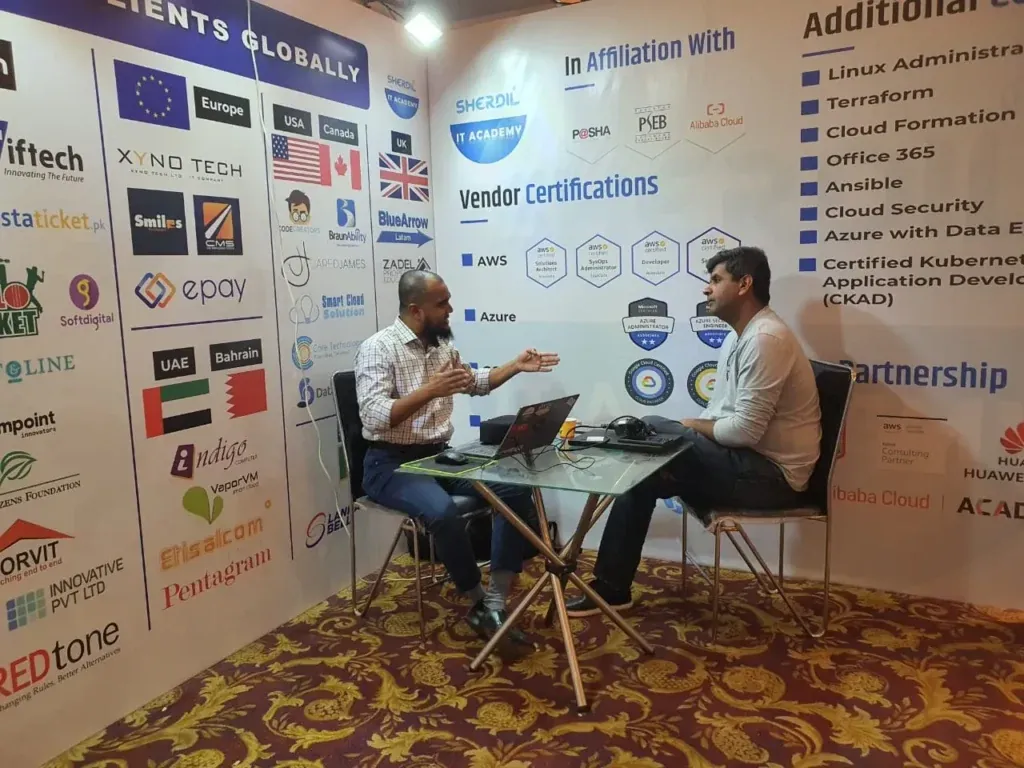 Seated discussion at the Sherdil booth beside the vendor certifications wall, ITCN Asia 2023