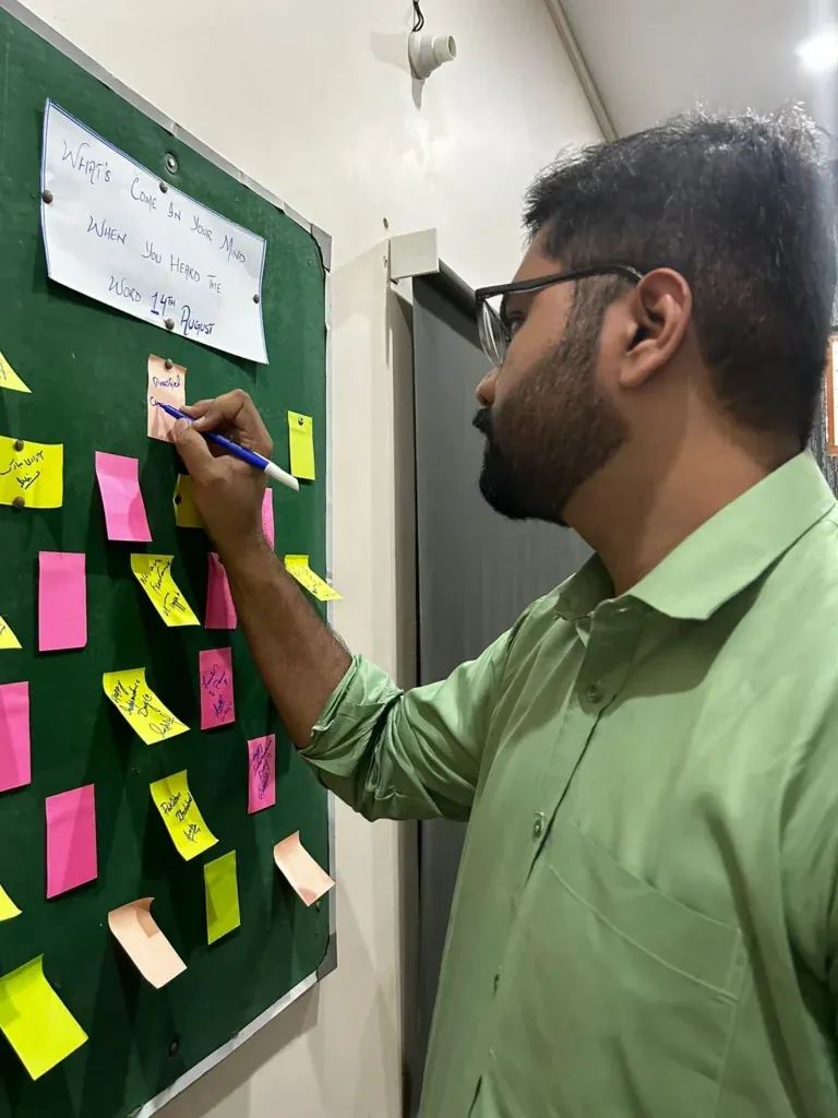 Team member writing a note on a message board, Sherdil Independence Day celebration 2023