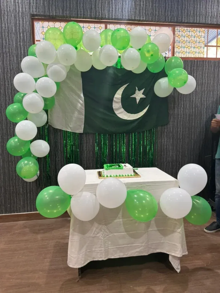 Independence Day cake table with green and white balloons and the Pakistan flag, Sherdil 2023