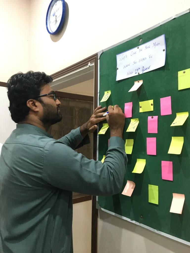 Team member pinning a note on the message board, Sherdil Independence Day 2023
