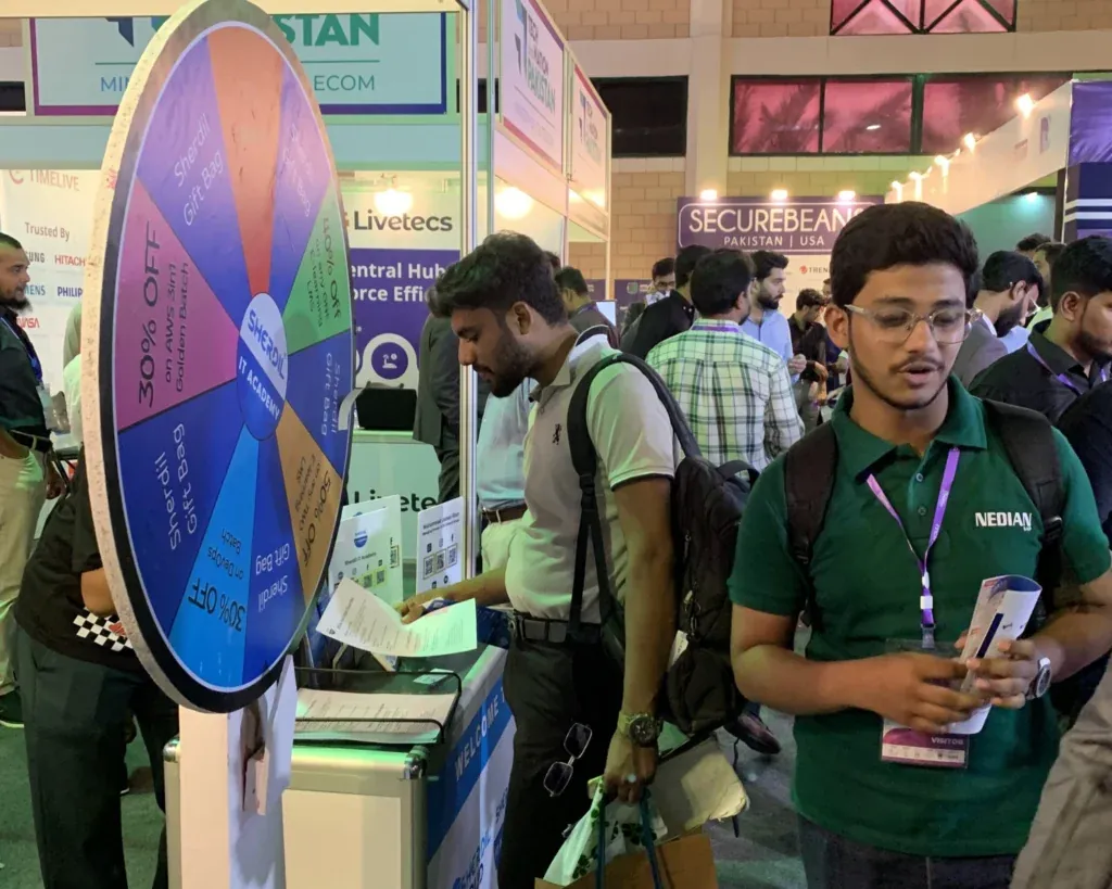 Students next to the Sherdil prize wheel, ITCN Asia 2025 Karachi