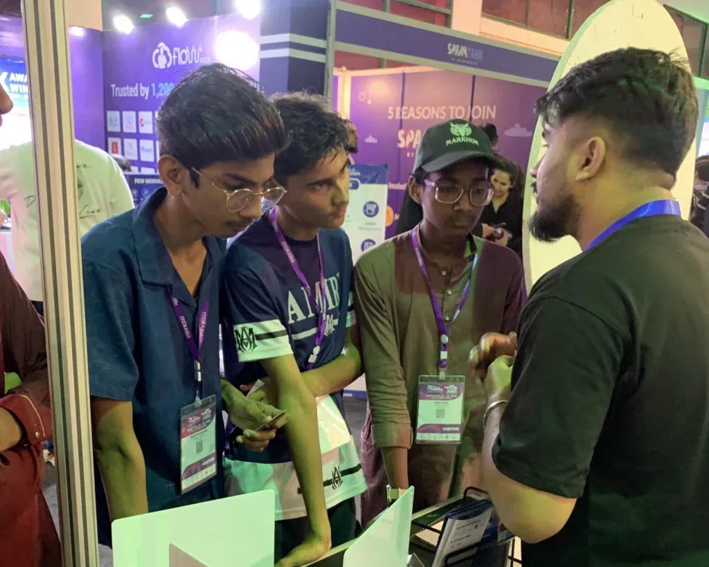Students with event badges talking to a Sherdil team member, ITCN Asia 2025