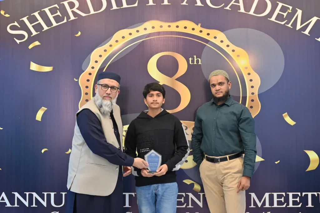 Young student holding an award shield with Sherdil mentors, 2025