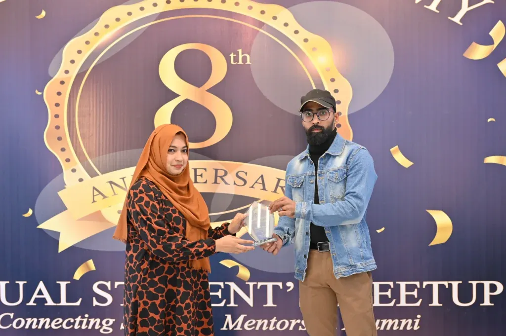 Award handover between two attendees at the Sherdil 8th Anniversary Meetup 2025