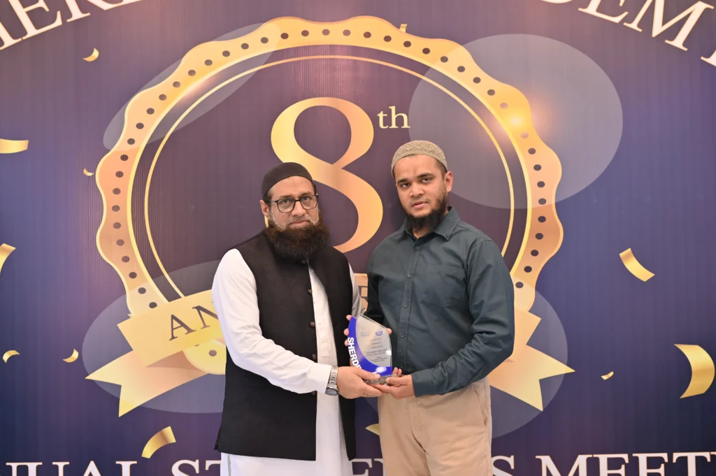 Award presentation in front of the 8th anniversary backdrop, Sherdil IT Academy 2025