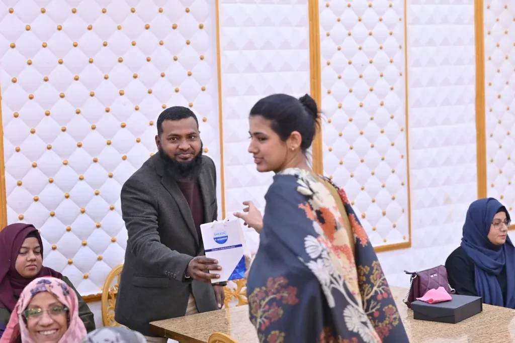 Attendee receiving a gift at a table, Sherdil 8th anniversary meetup 2025