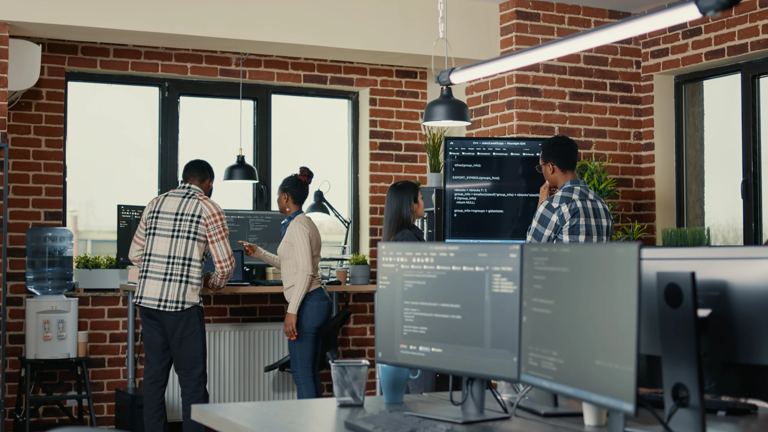 A team of cloud security professionals collaborating around monitors displaying code in a modern tech office, representing the growing but underserved cloud security career niche in Pakistan.