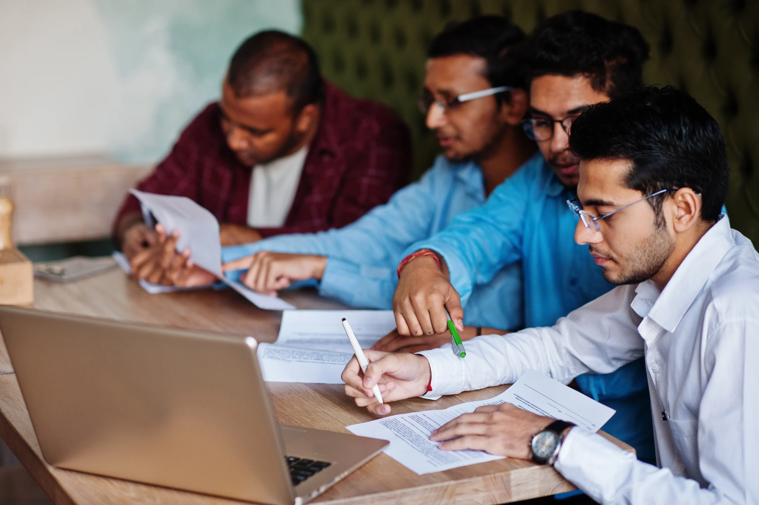 Pakistani engineers studying Kubernetes concepts together at a desk with a laptop and certification study materials, preparing for the CKA exam in 2026.
