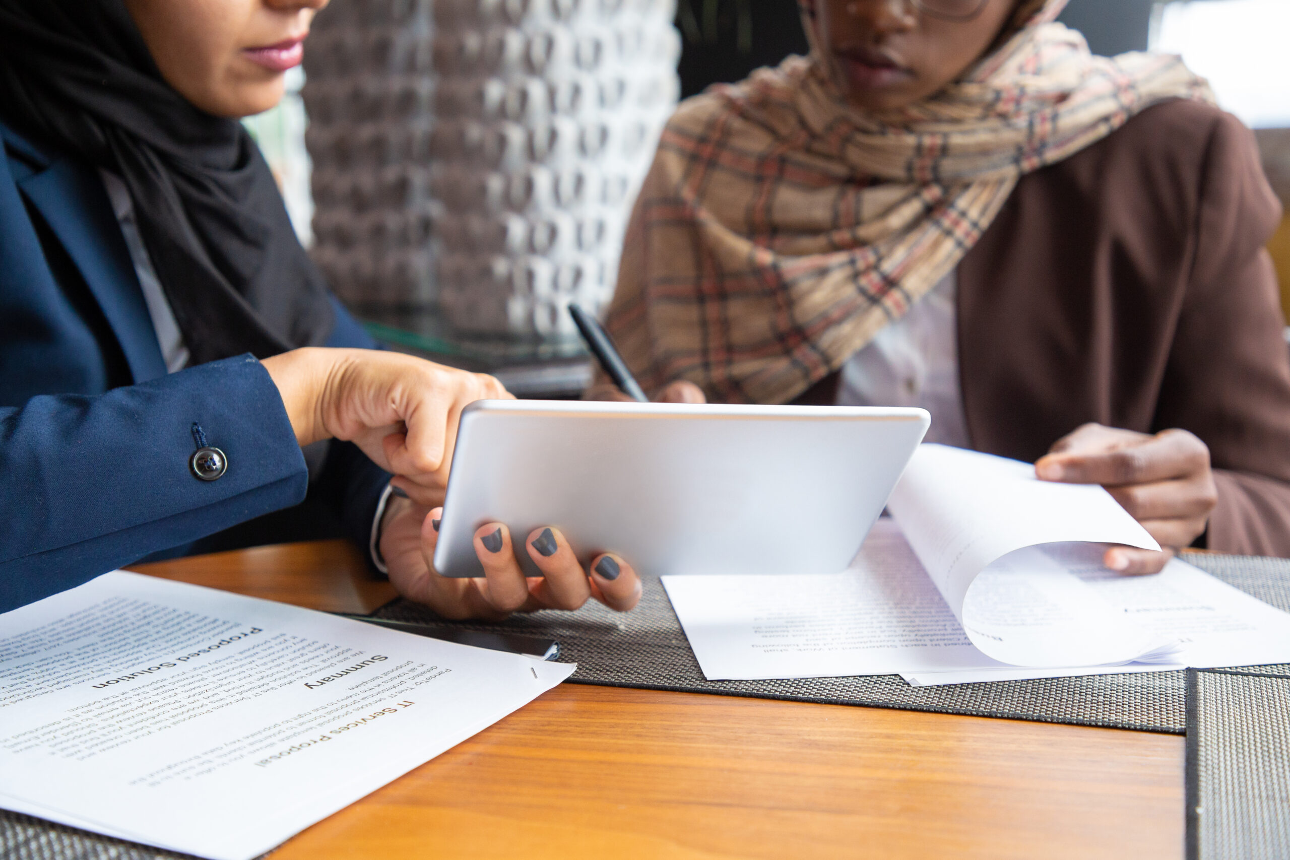 Two Muslim women professionals reviewing an IT services proposal and tablet together, representing the growing number of Pakistani women pursuing CISA certification and IT audit careers in 2026.